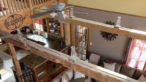 Un vaste espace de vie doté d’un haut plafond, de poutres apparentes, d’un canapé, d’une table basse et d’une table à manger.