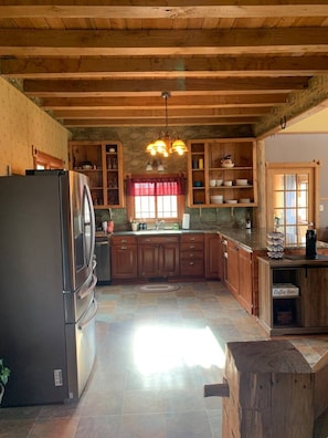 A kitchen with wooden cabinets, a stainless steel refrigerator, and a stone backsplash.