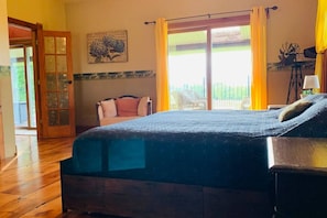 A bedroom with a bed, a chair, a window with curtains, and a door.