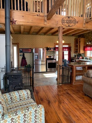 A rustic interior with a wooden staircase, a kitchen with modern appliances, and a cozy seating area.