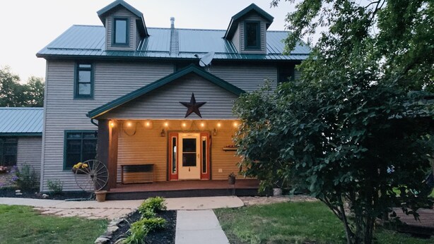 Une maison à deux étages avec un porche, une décoration en forme d’étoile et une antenne parabolique.