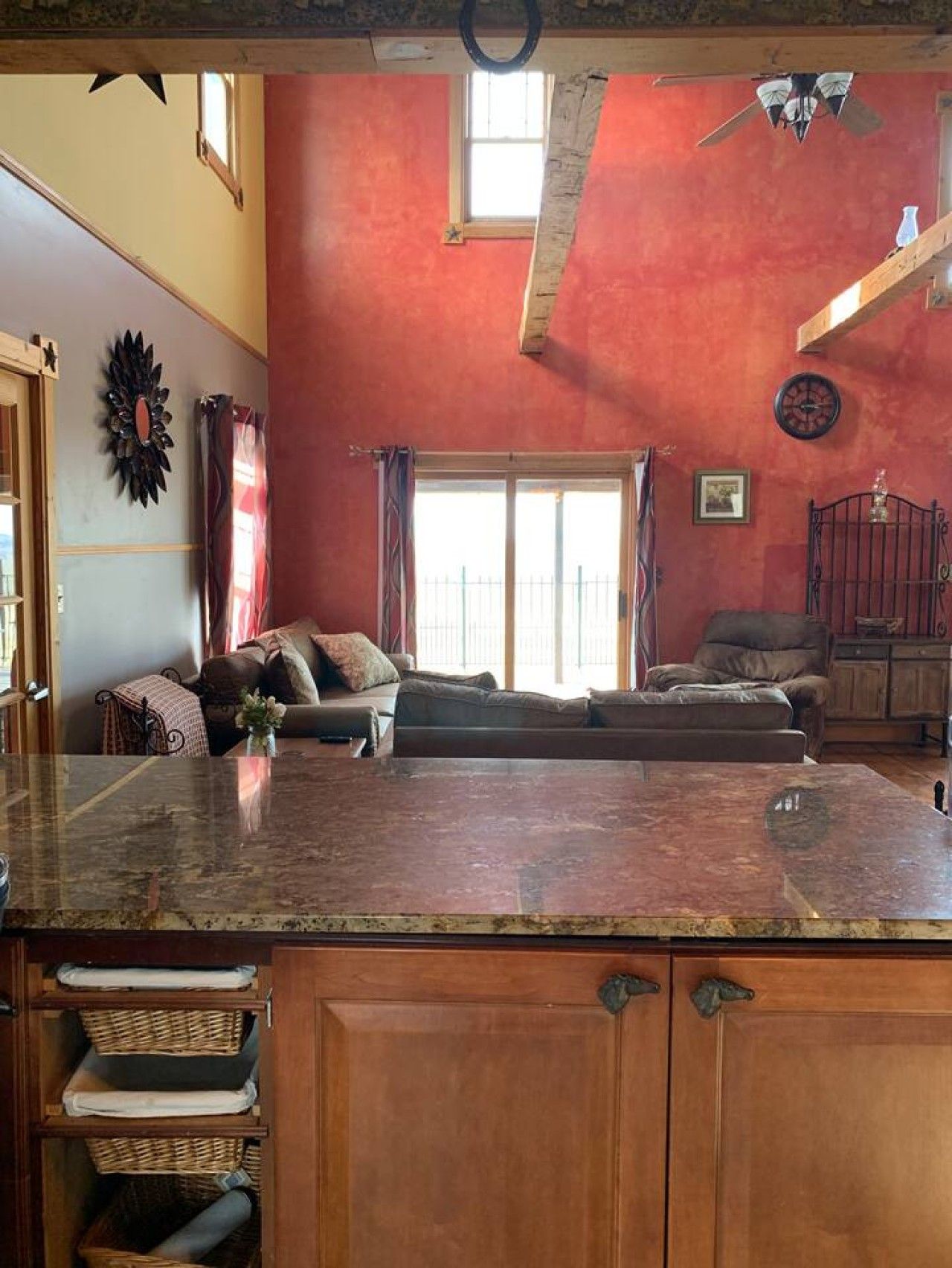 Una sala de estar con un ventanal grande, chimenea y una zona de cocina con encimera de granito.