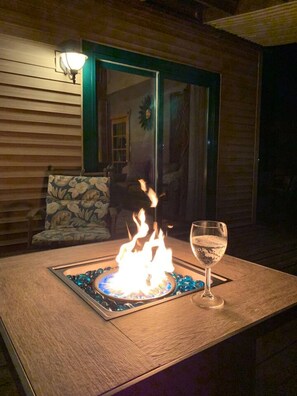 A table with a glass of water and a lit fire feature.