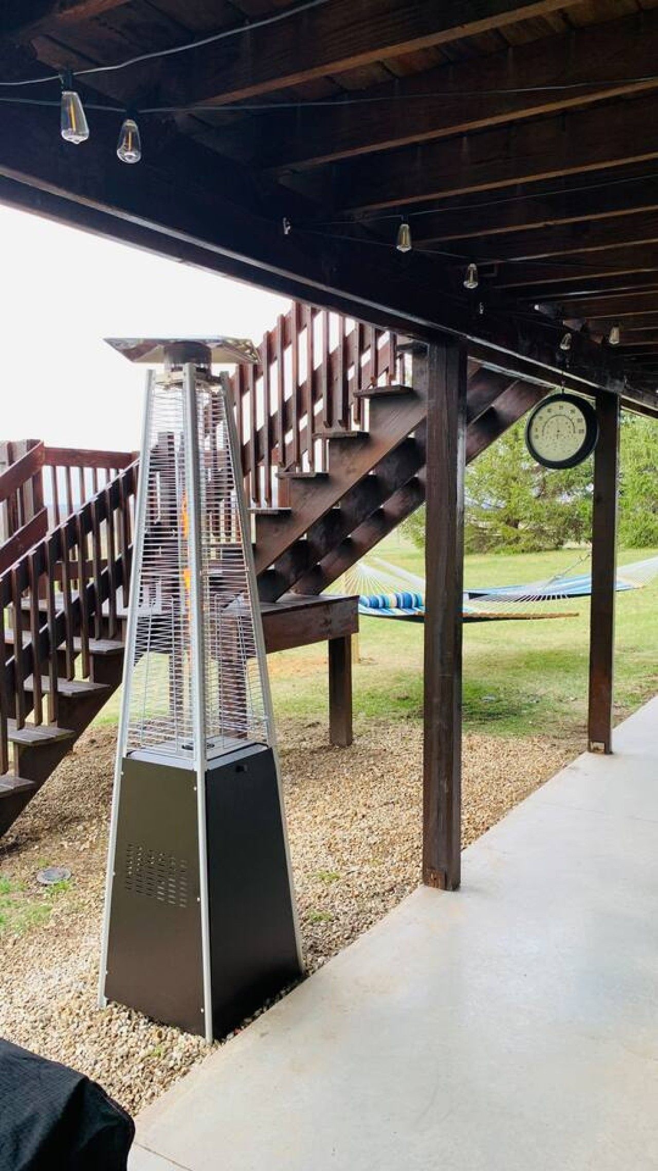 Un espacio al aire libre cubierto con estructura metálica, escaleras de madera y un reloj en la pared.