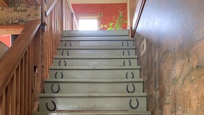 Un escalier avec des rampes et des marches en bois, dotées de poignées en forme de fer à cheval.