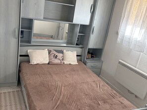 A bedroom with a bed, a wardrobe, a mirror, and a radiator. - Air-conditioned apartment with parking 450m from beaches (Argelès-sur-Mer)