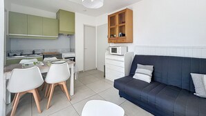 En kompakt bolig med tekøkken, spiseplads og sofa.