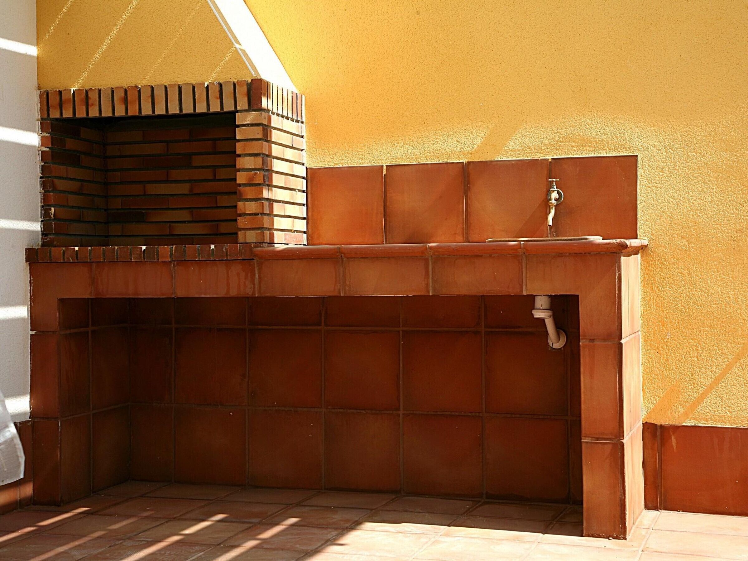 A brick-built outdoor kitchen with a built-in sink and a chimney.