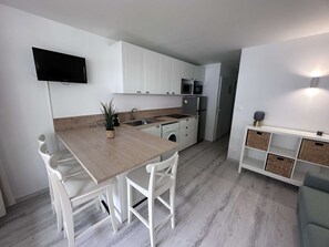 A compact kitchen with white cabinets, a wooden countertop, a built-in microwave, and a washing machine. - 2-room apartment with pool, tennis and private parking 50m from the beach (Port Camargue)