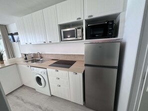 A modern kitchen with a stainless steel refrigerator, a microwave, a washing machine, and a sink. - 2-room apartment with pool, tennis and private parking 50m from the beach (Port Camargue)