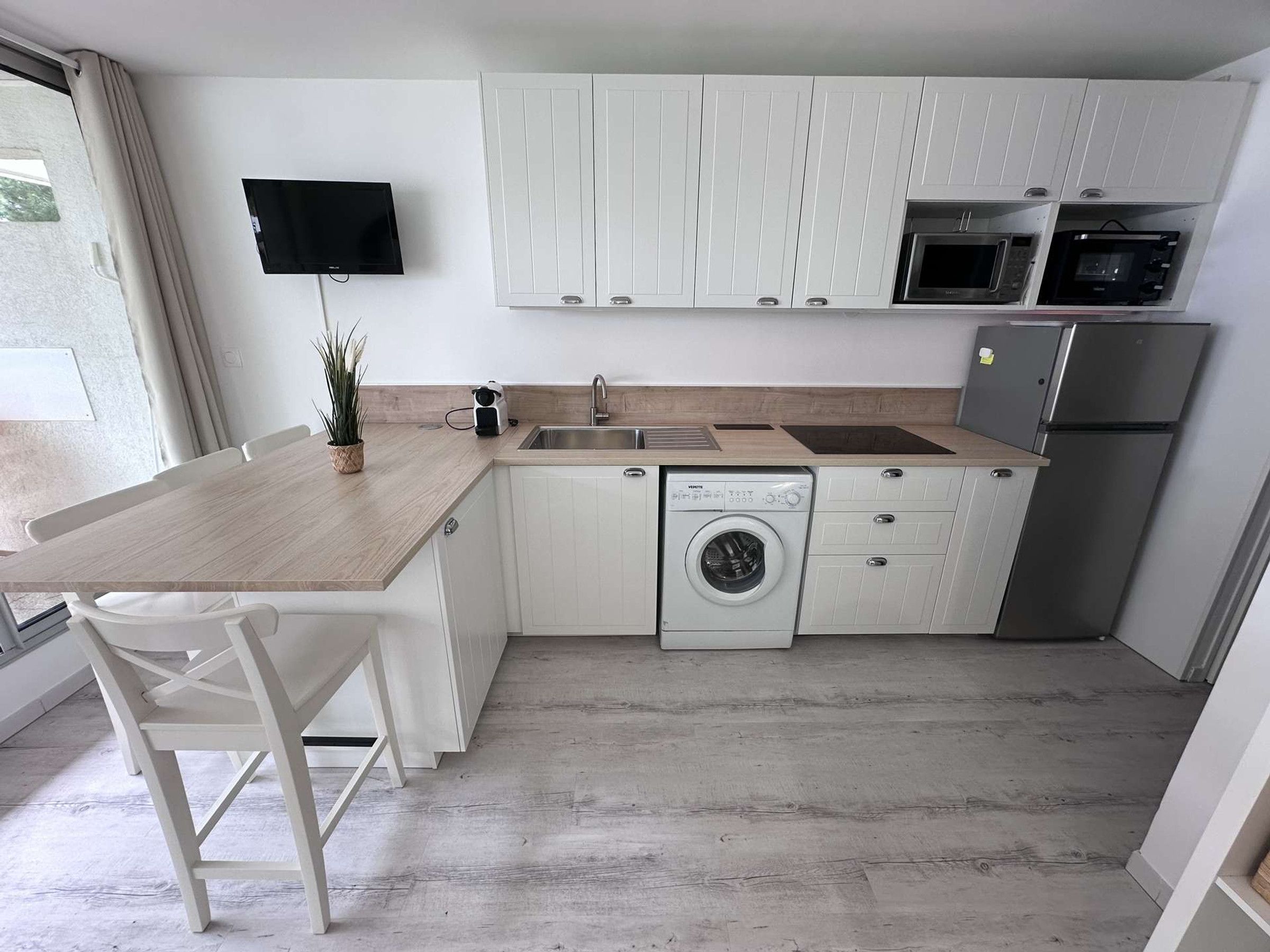 Cocina compacta con lavadora, microondas y refrigerador.