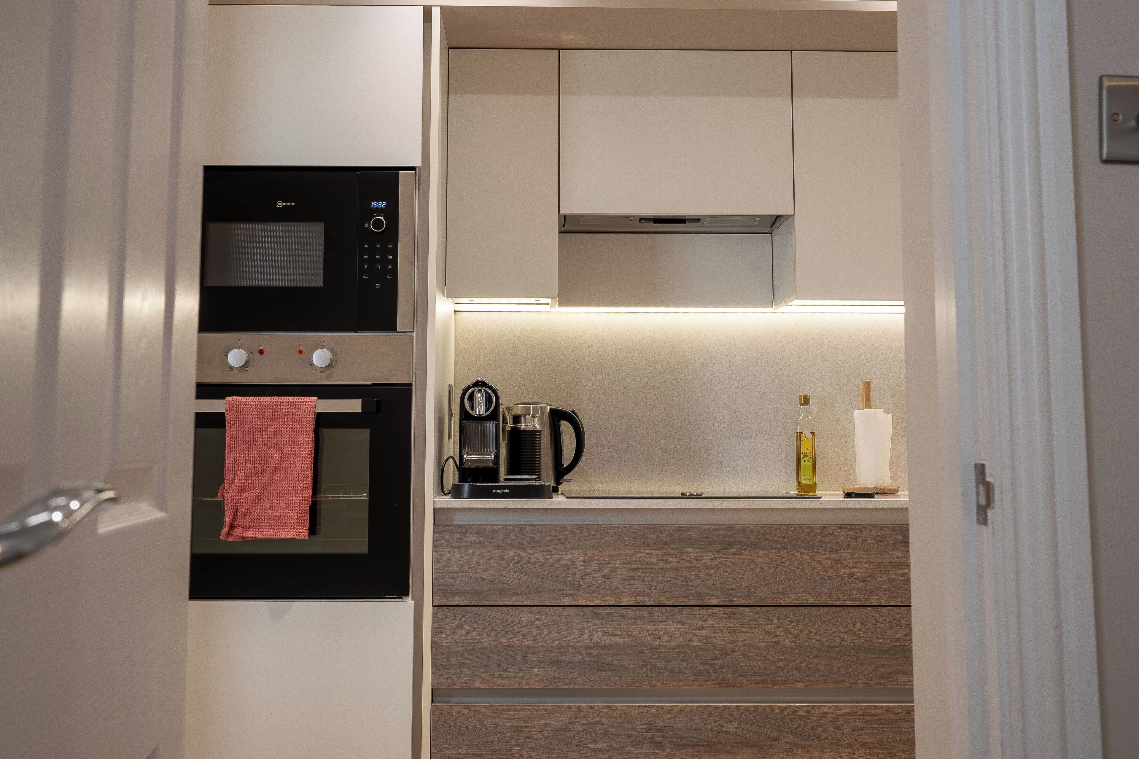 A compact kitchen with a built-in microwave, oven, and coffee maker.