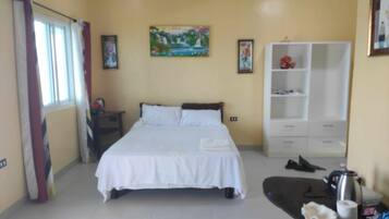 A bedroom with a bed, a wardrobe, and a painting on the wall.