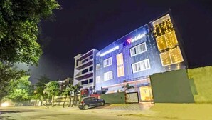 A multi-story hotel with a modern facade, illuminated windows, and a gated entrance. - Hotel Veridian (Lucknow)