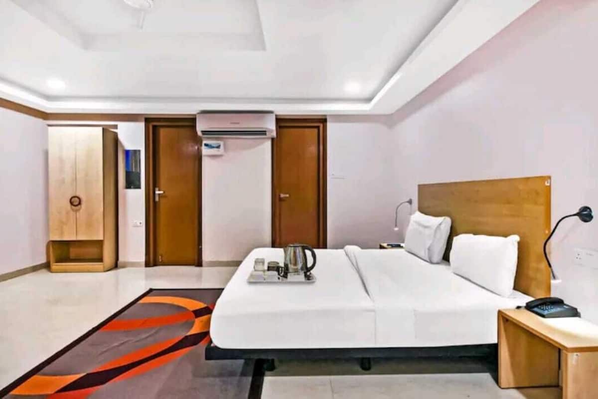 A hotel room with a bed, bedside table, and a small wooden cabinet.