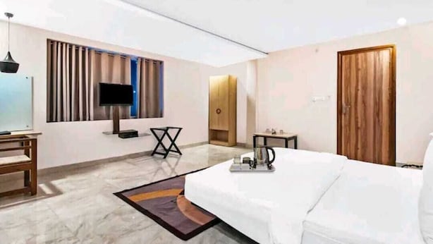 A modern hotel room with a bed, a television, a desk, and a coffee maker. - Hotel Veridian (Lucknow)