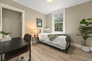 A bedroom with a bed, bedside table, lamp, chair, and a window with a view. - Walk to Todos Santos | Historic Downtown Delight (Concord)
