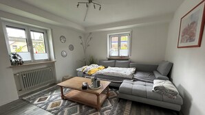 Ein modernes Wohnzimmer mit einem grauen Sofa, einem Holztisch und einem gemusterten Teppich.