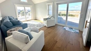 Un salon spacieux avec un plafond haut, de grandes fenêtres et une vue sur l’extérieur.
