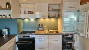 Una cocina moderna con armarios blancos, lavavajillas Bosch y horno integrado.
