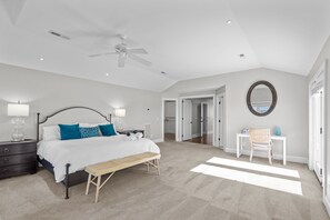 A bedroom with a bed, bedside tables, a bench, a desk, and a chair.