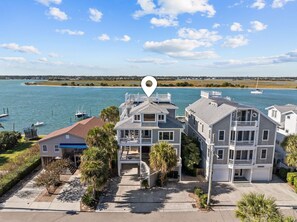 A coastal residential area with multiple two-story houses, a marina with boats, and a clear view of the ocean.