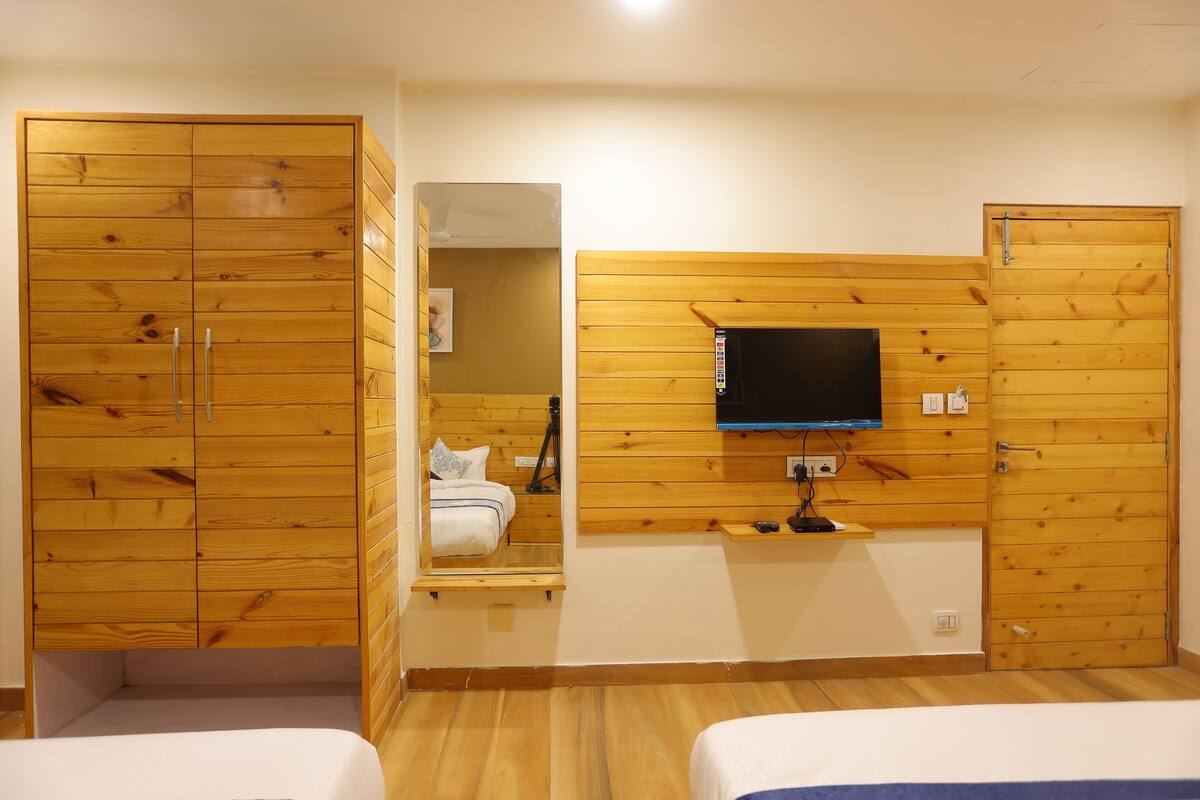 Un dormitorio con paneles de madera, un televisor montado en la pared y una cama con cabecera azul.