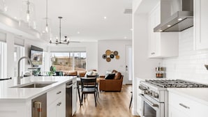 A modern kitchen with white cabinetry, stainless steel appliances, and a central island.