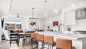 A modern kitchen with a large island, bar stools, and pendant lighting.