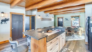 A spacious kitchen with a granite countertop, wooden cabinets, and a high ceiling with exposed beams. - Lakefront New Hampshire Hideaway w/ Deck & Views (Errol)