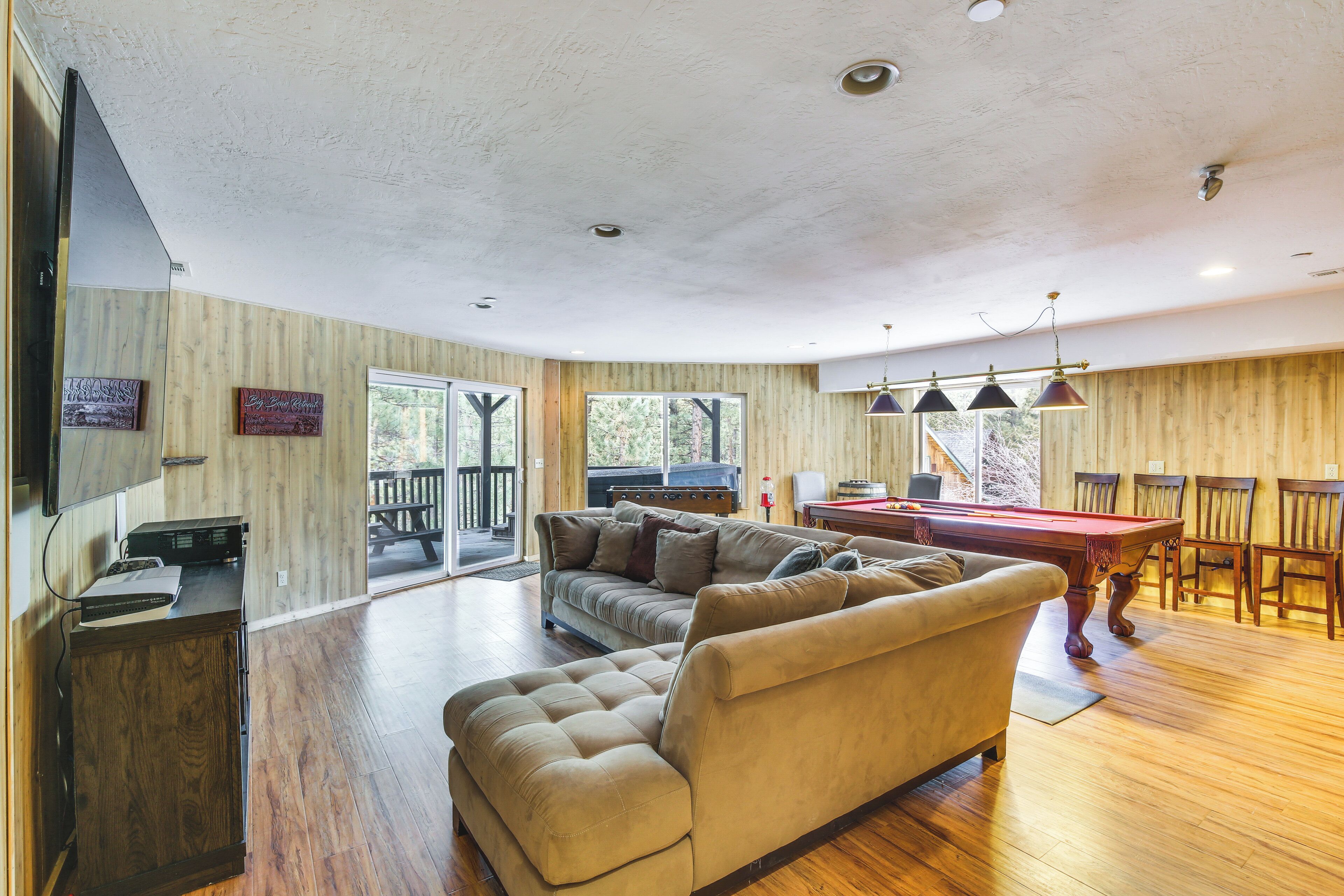 A spacious living room with a pool table, a sofa, and a dining area with chairs.
