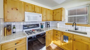 A kitchen with wooden cabinets, a white microwave, a gas stove, and a sink. - Mountain Home w/ Deck: 1 Mi to Angel Fire Resort! (Angel Fire)