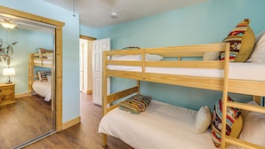 A bunk bed room with a wooden ceiling fan, a mirror, and a wooden nightstand with a lamp. - Mountain Home w/ Deck: 1 Mi to Angel Fire Resort! (Angel Fire)