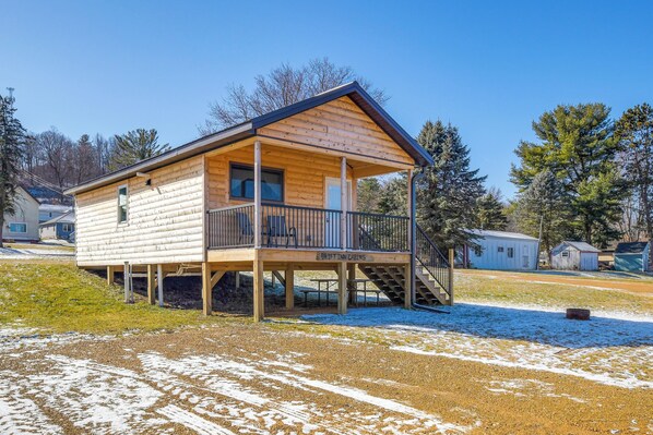 A wooden cabin with a porch and a staircase leading to a deck.
