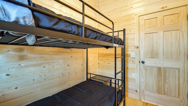 Habitación con literas, paredes de madera y una puerta.