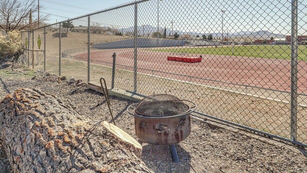 A fenced sports field with a track and a grill area.