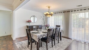 A dining room with a chandelier, a round mirror, and a view of the outdoors through large windows. - Family-friendly Loma Linda Retreat: Walk to LLU (Loma Linda)