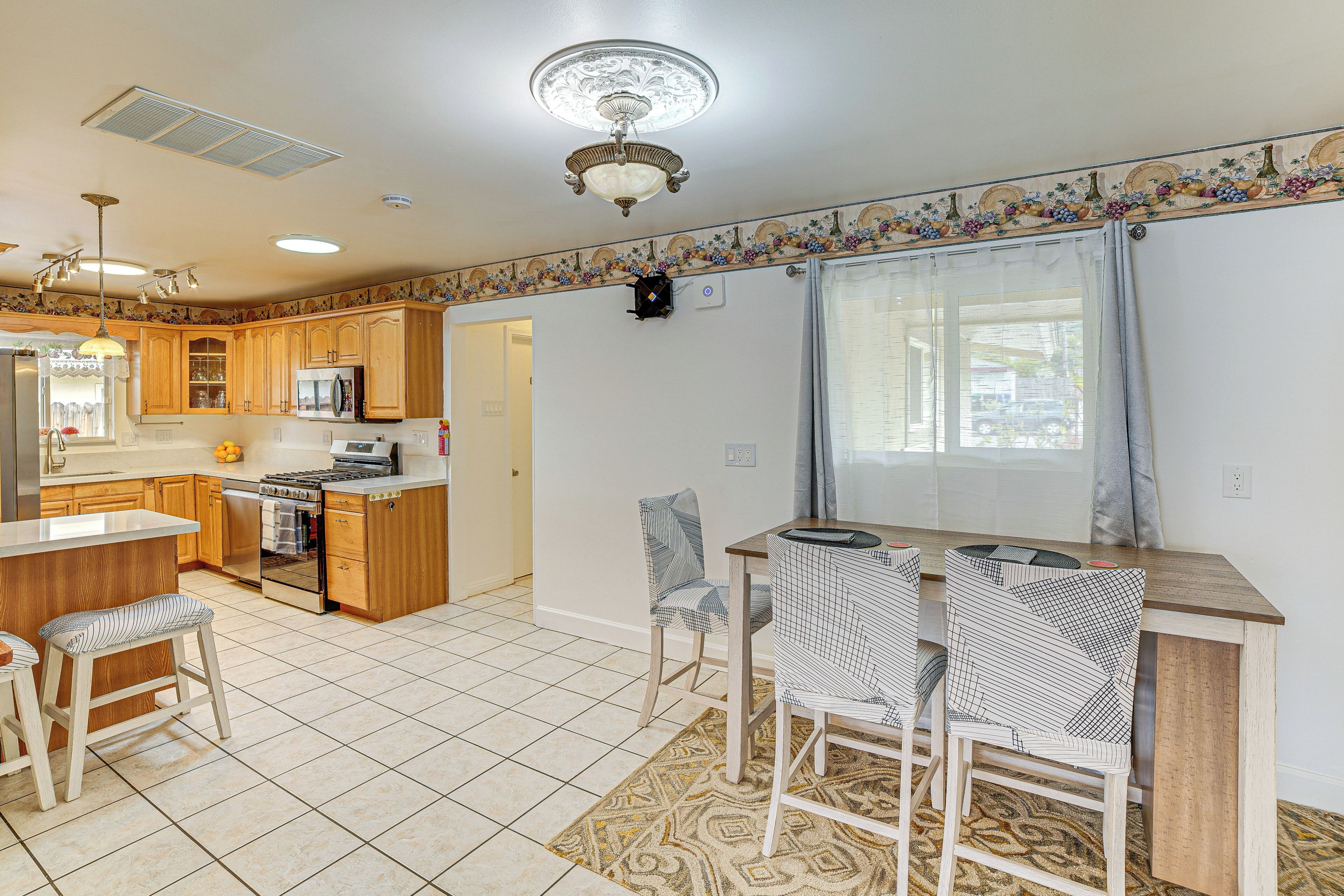 A modern kitchen with wooden cabinets, a central island, and a dining area with patterned chairs.