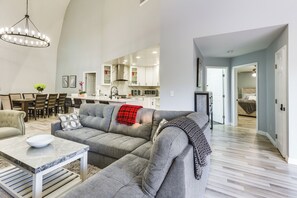 A spacious living room with a grey sofa, a marble coffee table, and a chandelier.