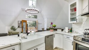 Una cocina moderna con armarios blancos, horno integrado y una isla grande con lavavajillas.