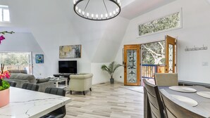 Amplia sala de estar con mesa de comedor, asientos cómodos, televisor de pantalla plana y un gran ventanal con vistas al exterior.