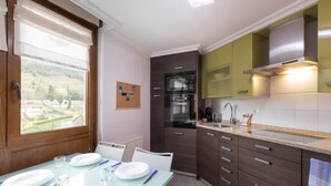 A modern kitchen with a dining area, featuring a built-in oven, microwave, and a large window. - Ekain - baskeyrentals (Zestoa)