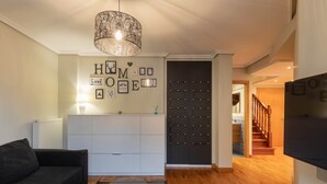 A living room with a sofa, a coffee table, a pendant light, a wall with framed pictures, and a staircase leading to another room. - Ekain - baskeyrentals (Zestoa)