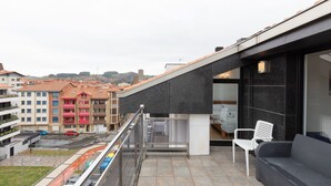 Un bâtiment moderne doté d’un balcon, d’une porte vitrée et d’un espace salon comprenant une chaise et un canapé.