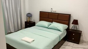 A bedroom with a bed, two nightstands, a lamp, and a curtain. - Everluxe Residence  (Abidjan)