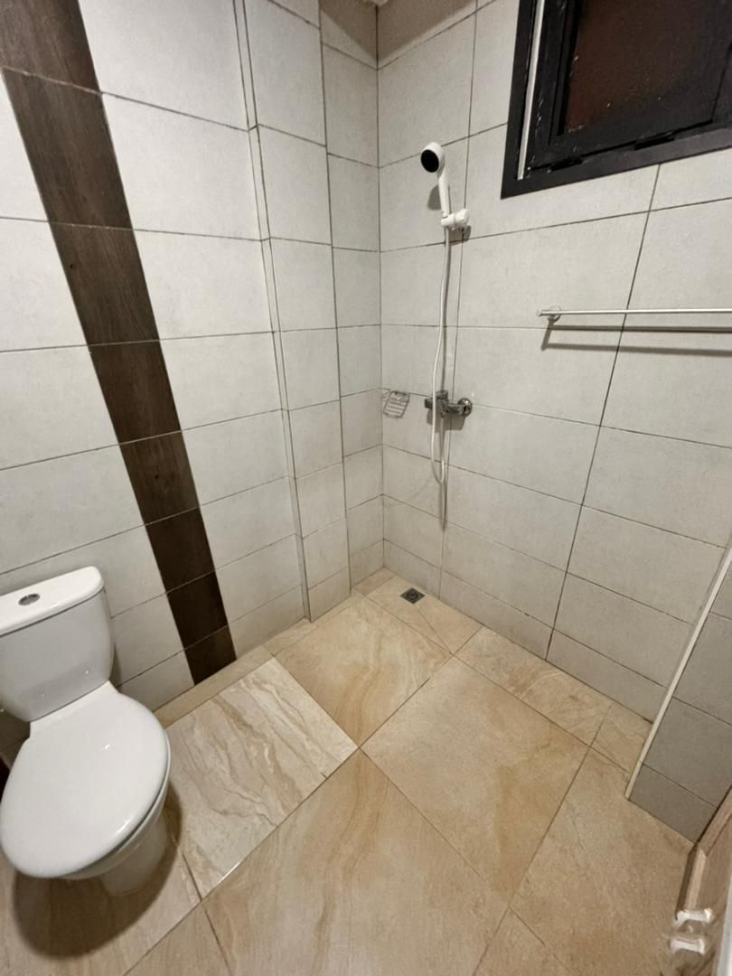 A small bathroom with a toilet, a shower, and a towel rack.