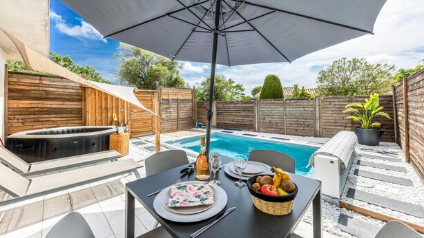 A backyard with a pool, a hot tub, and a dining table set for two. - Stunning home in Roquefort Les Pins (Roquefort Les Pins)