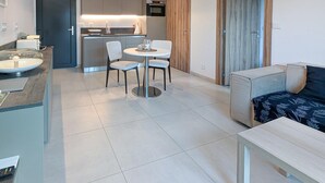 A modern kitchen with a central island, a dining area with two chairs, and a sofa with a patterned cover. - Stunning home in Roquefort Les Pins (Roquefort Les Pins)