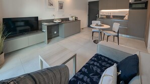 A modern living room with a flat-screen TV, a sofa with patterned cushions, and a dining area with a small table and chairs. - Stunning home in Roquefort Les Pins (Roquefort Les Pins)