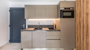 A compact kitchen with a built-in oven, a sink, and a wooden cabinet. - Stunning home in Roquefort Les Pins (Roquefort Les Pins)